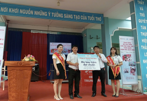 Ông Nguyễn Quốc Hiếu - Hiệu trưởng nhà trường tiếp nhận mũ bảo hiểm từ ông Đỗ Thanh Tùng - Cửa hàng trưởng Head Honda Tân Hồng